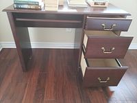 Front view of wooden desk showing three drawers on the right side and a non-pulled keyboard tray under the desktop.