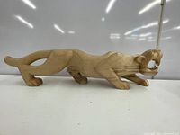 Full side view of the vintage hand carved wooden cougar sculpture showing its crouching pose and detailed carving.