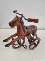 Front angle of vintage wooden horse tri-cycle showing detailed wood carving and tri-cycle wheels.