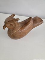 Side angled view of the wooden owl showing detailed carving on the head, wings, and tail.