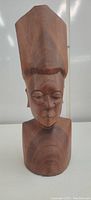 Front view of a wooden bust showing the figure's facial features and tall headgear.