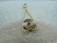 Close-up image of the 10K gold triangular pendant showing the rope textured outer edge and coiled rope circle center on a soft fabric background.
