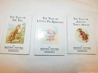 Front view of three Beatrix Potter children's books with illustrated covers, showing titles and author names.