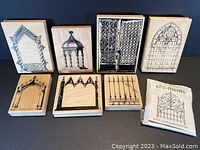 Top view of 8 wood-mounted rubber stamps showing architectural design impressions on the wood blocks including gates, windows, arches, and frames.