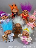 Group photo of seven assorted troll dolls, showing colorful hair and outfits typical to the lot.