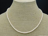 Full front view of the blush cream pearl necklace on display bust showing uniform pearls.