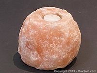 Front view of pinkish Himalayan salt candle holder with visible rough natural texture and inset for candle.