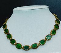 Full view of the Italian Florentine necklace displayed on white fabric bust showing translucent hunter green oval glass beads outlined in gold, separated by gold-colored filigree beads.