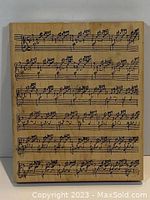 Front view of the rubber stamp showing the printed sheet music design on the wooden block.