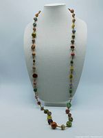 Front view of the full length necklace displayed on neck form showing mixed bead types and colors.