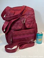 Front view of the burgundy Lug Puddle Jumper bag showing pockets and shoulder strap alongside soda can for size reference.
