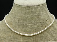 Front view of pearl necklace displayed on a mannequin bust showing lustrous cream-colored pearls arranged in a single strand.
