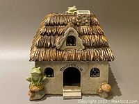 Front view of Toad Hollow cottage with visible thatched roof, entrance, windows, and toad decorations, showing overall size and shape.