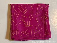 Folded view of purple-pink Echo silk scarf with yellow linear pattern and visible Echo logo embroidered near edge.