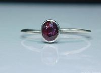 Close-up front view of vintage ring showing oval garnet stone set in sterling silver bezel with thin band.