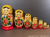All seven colorful handpainted nesting dolls displayed in a row by size from largest to smallest.