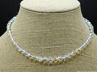 Full front view of the necklace displayed on a beige mannequin, showing the faceted clear crystal beads reflecting light.