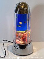 Overall front view of the vintage tropical fish aquarium light showing the cylindrical clear casing with moving fish illusion inside and chrome-colored base and top.