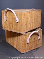 Two stacked rectangular wicker baskets with fabric lining and light-colored suede handles, shown from the front
