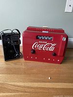 Front shot of red Coca Cola radio with tuning dial and black portable radio beside it