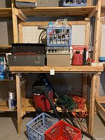 Wide view of the shelf and floor showing toolboxes, red gas can, milk crates, vacuum, and extension cords.