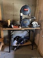 Ryobi band saw, Craftsman circular saw and other tools on a work table in basement