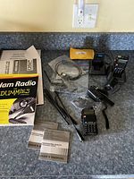 Two Baofeng UV-5R FM transceiver radios on charging bases with antennas, battery chargers, and carrying straps on kitchen counter, showing accessories.