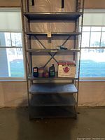 Tallest metal shelving unit with six shelves, some items on shelves for scale only, unit is grey metal with perforated shelves and cross-brace support at back.