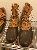 Front view of the pair of men's vintage LLBean duck boots with brown leather upper and dark rubber lower.