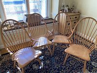 Four Windsor chairs arranged in a room on patterned carpet in front of a window