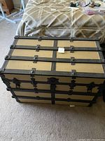 Closed view of the antique steamer trunk showing exterior metal reinforcements and latches.