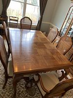 Photo showing parquet top dining table with six chairs around it, including two captain chairs with arms.