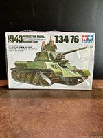 Front of the sealed Tamiya box showing painted illustration of the 1943 Russian T-34/76 tank model with two crewmen, tank in olive green.