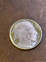 Obverse side of silver coin showing Native American profile with feathers and braided hair, marked 2023 and LIBERTY.