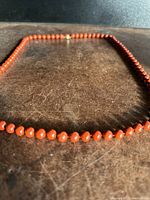 Natural red coral bead necklace spread on a surface, showing bead texture and color.