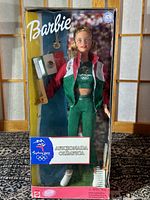 Front view of the Barbie doll in original packaging holding a Mexican flag, dressed in green and red tracksuit with Sydney 2000 Olympics logos.
