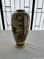 Front and side views showing floral and bamboo hand-painted decoration with birds and gold accents on rim and base