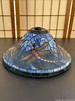 Full view of conical stained glass lampshade with dragonfly design in blue and green mosaic glass pieces.