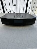 Front view of the black Bose alarm clock showing the speaker grille and digital display screen under natural light.