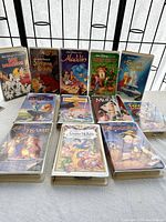 Front view of 14 Disney VHS tapes arranged in rows showing cover art and titles.