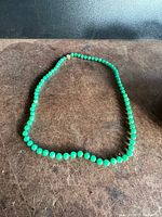 Full view of the necklace arranged on a flat surface showing bead size, color, and overall length.