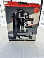 Front of original box showing Krups IL Primo espresso machine and promotion for 4 free flavored syrups.