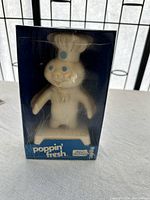 Front view of Pillsbury Poppin' Fresh doll in original sealed box showing doll inside and box front labeling.