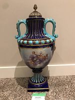 Front elevation showing cobalt blue body, turquoise applied handles, gilt ribbing and one classical figural panel.