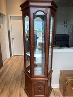 Front view of full wooden corner cabinet showcasing glass upper section and wood lower cupboard.