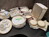 Multiple stacks of plates in fabric storage bags and tea set pieces on table.