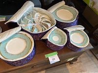 Four quilted purple zippered carriers holding stacks of Melrose china plates and cups in protective sleeves
