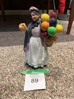 Front view of the Royal Doulton Biddy Pennyfarthing figurine showing the multicolored balloons and bouquet.