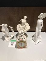 Three figurines and one clock displayed side by side on wooden background showing overall set.