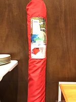 Red canvas umbrella cover with label showing 'Canvas Red Market Umbrella', packaging showing the product and dimensions (diameter 9 feet, height 7.5 feet).